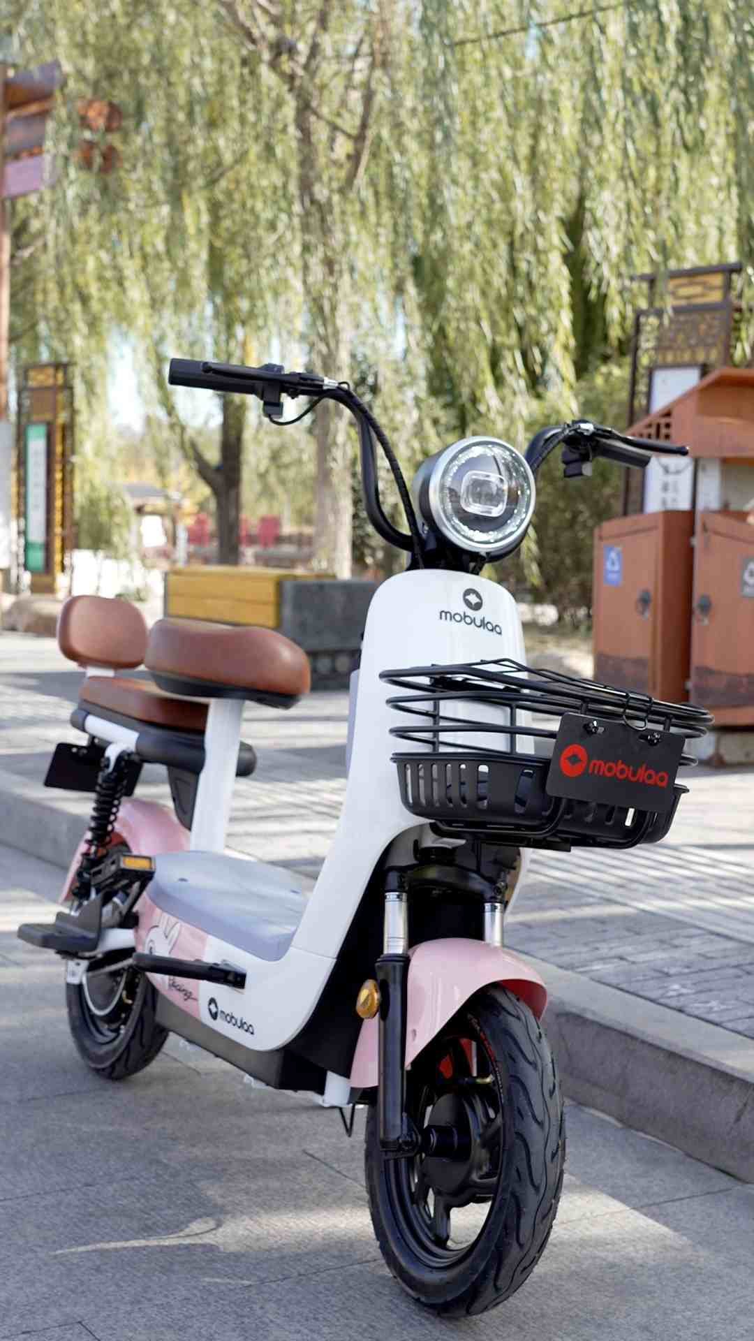 moto eléctrica Mobulaa en color blanco y rosa con asiento doble y canasta delantera