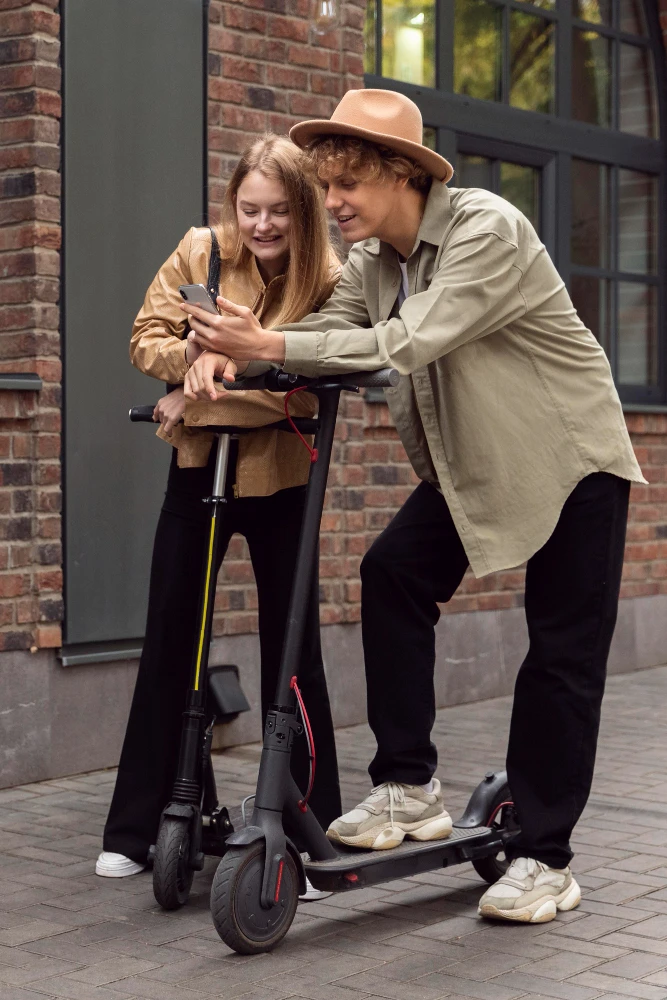 Pareja disfrutando su scooter eléctrica mientras revisan su celular en la ciudad, movilidad moderna y divertida.