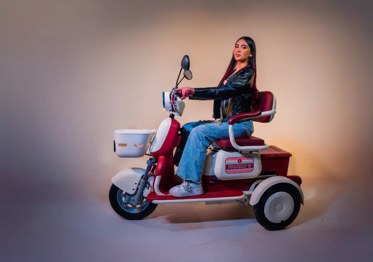 Persona sentada en scooter eléctrico Family Q Evobike modelo B, con asiento acolchado y canasto frontal, ideal para transporte práctico.