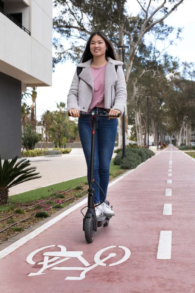 Persona usando patineta eléctrica en ciclovía urbana, ejemplo de movilidad eléctrica sostenible.