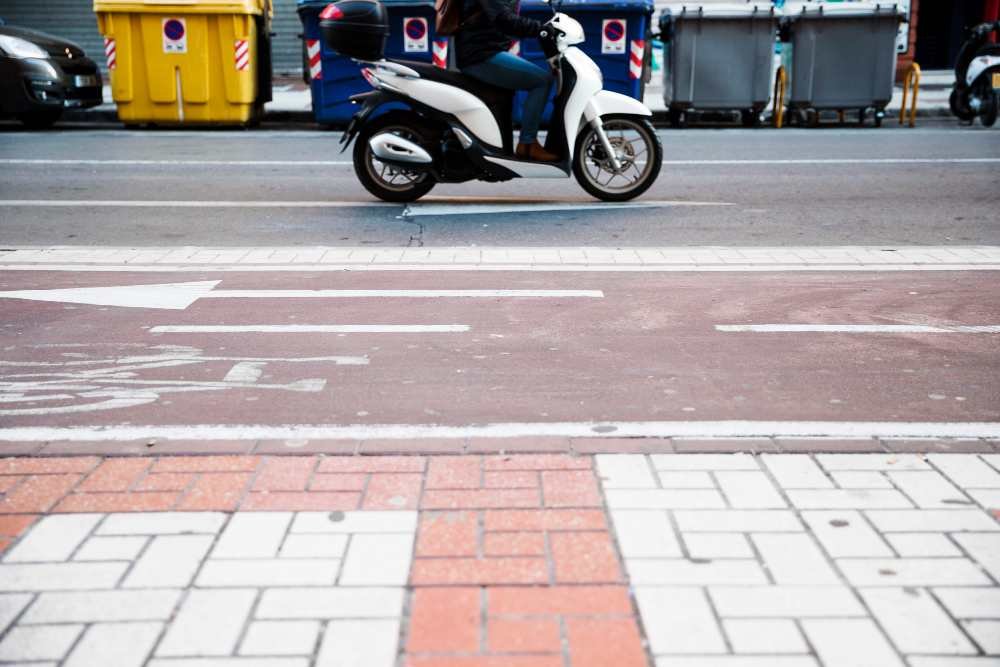 Motocicleta electrica circulando por una vía urbana con señalización de tránsito, ejemplo de movilidad regulada según la Ley 2486 de 2025