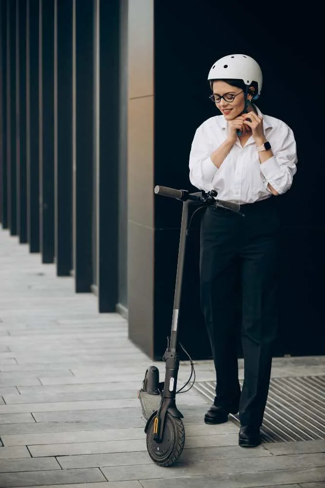 Mujer ajustando casco junto a scooter eléctrico, práctica de seguridad vial promovida por la Ley 2486 de 2025